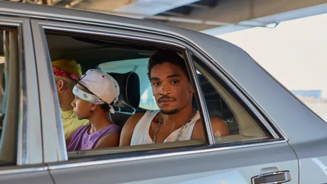 A dog sitting in the back seat of a moving car, looking toward the window
