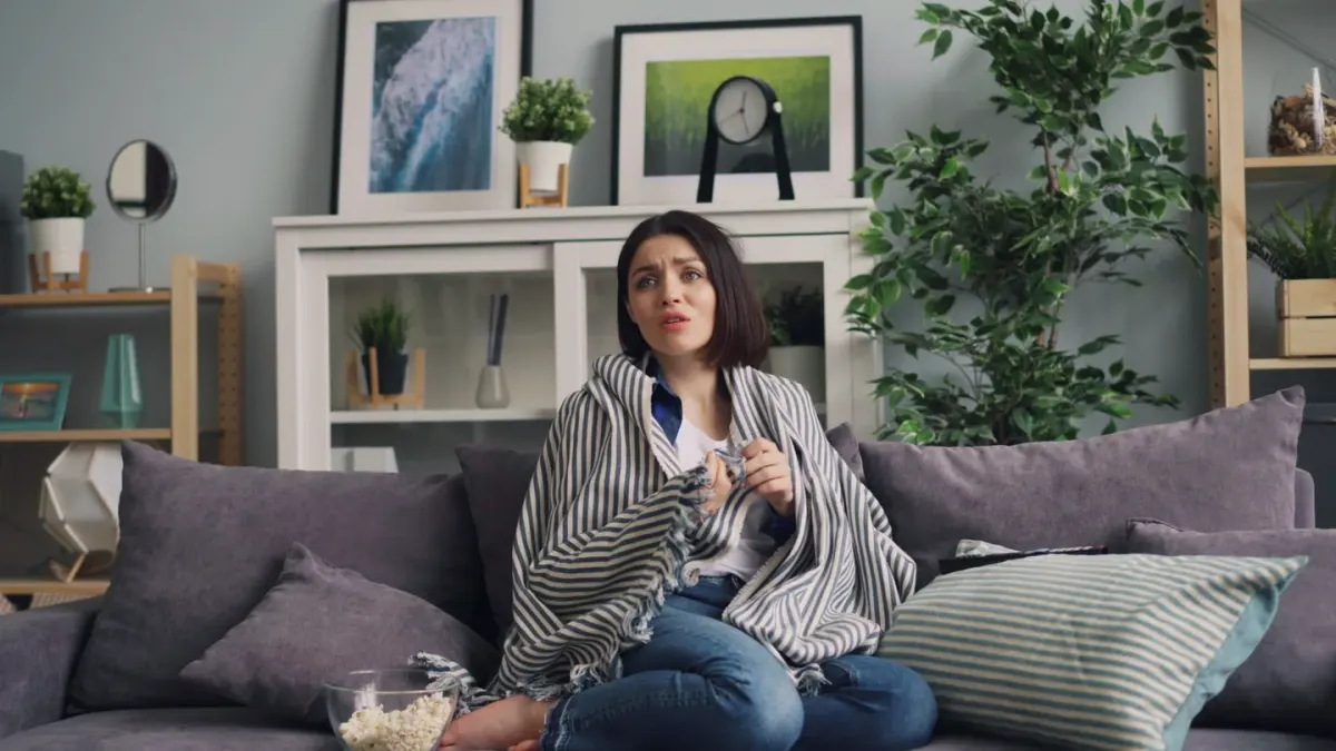 A dog sitting near a bowl of plain popcorn on a living room couch