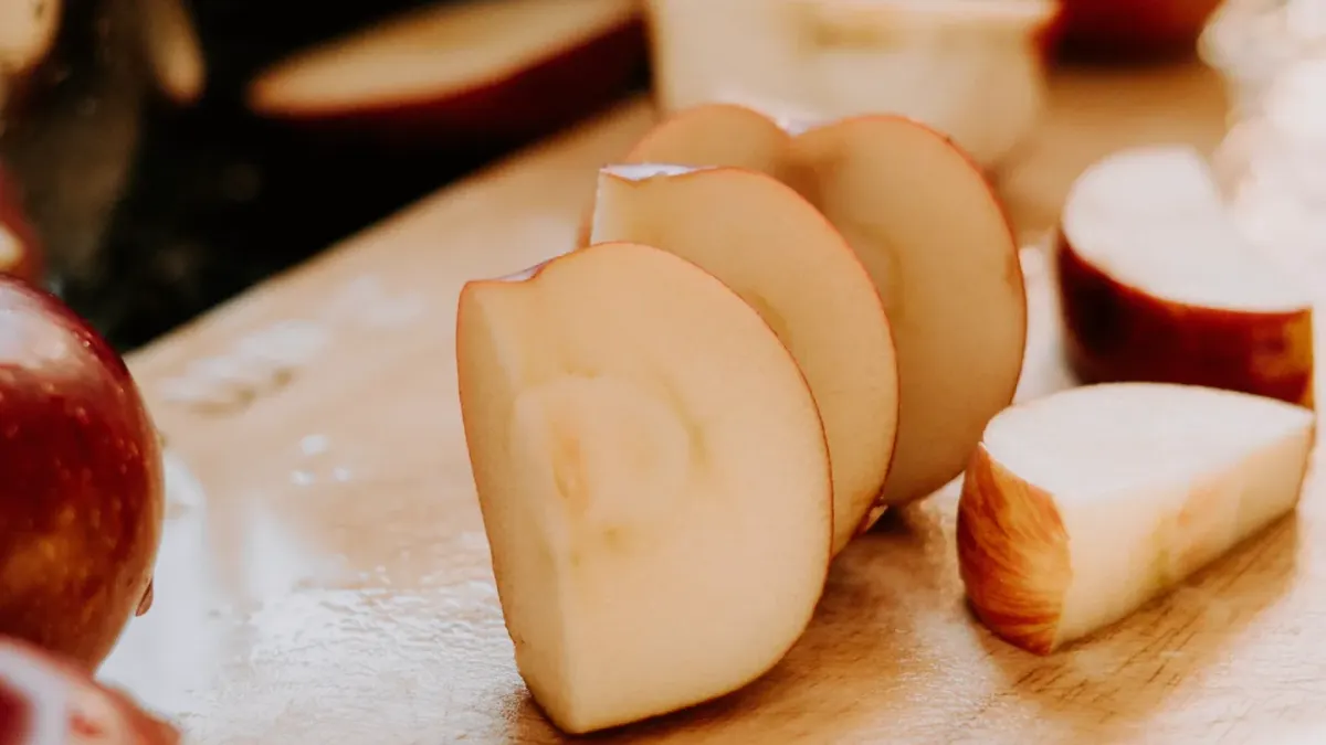 A golden retriever standing near sliced apple pieces on a kitchen counter