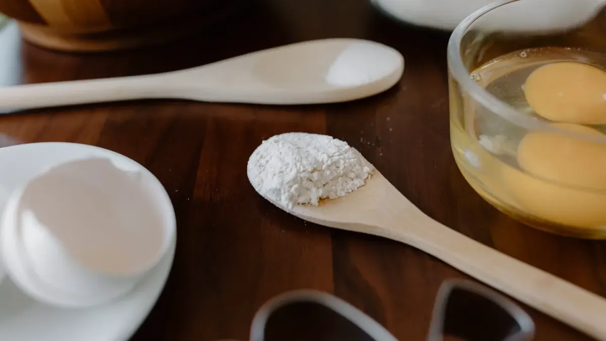 A scoop of hydrolyzed collagen powder next to fish skin scraps on a wooden counter
