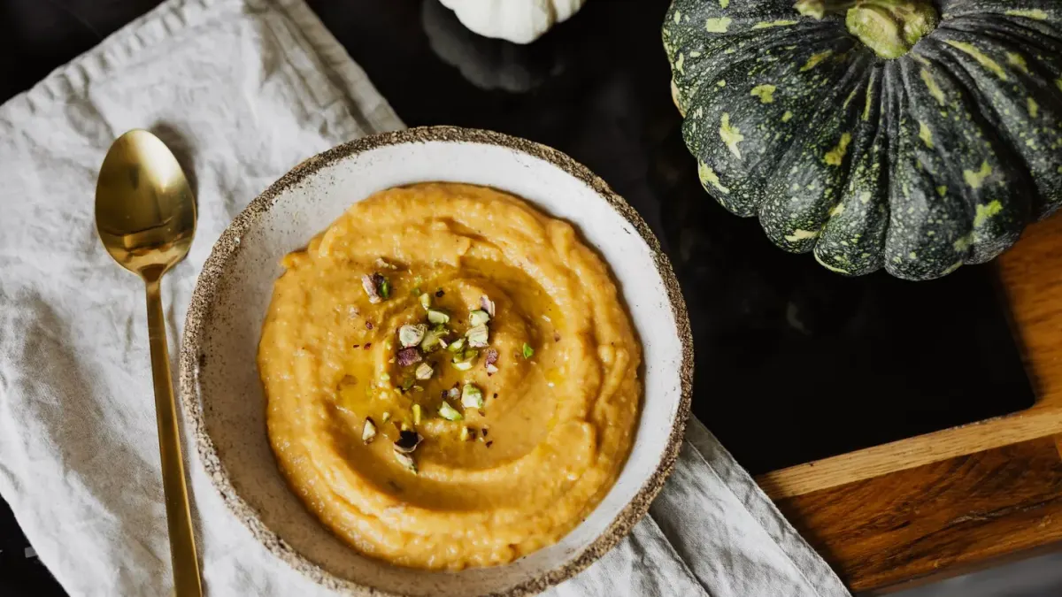 A spoonful of canned pumpkin puree next to a dog's stainless steel food bowl