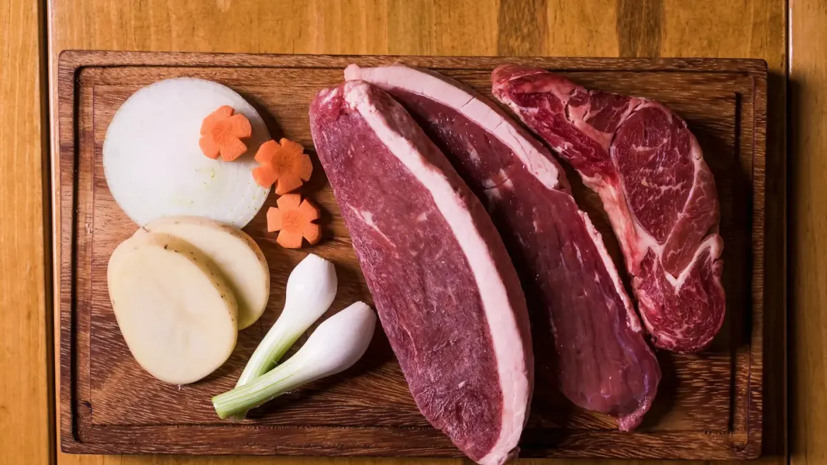 Chopped onion on a cutting board next to a dog looking up from the kitchen floor