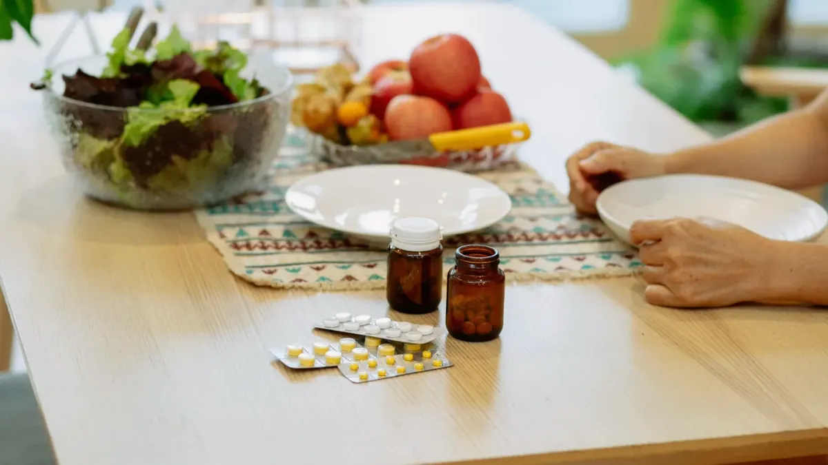 Dog owner spacing out a pill and a small probiotic supplement dish on a kitchen counter
