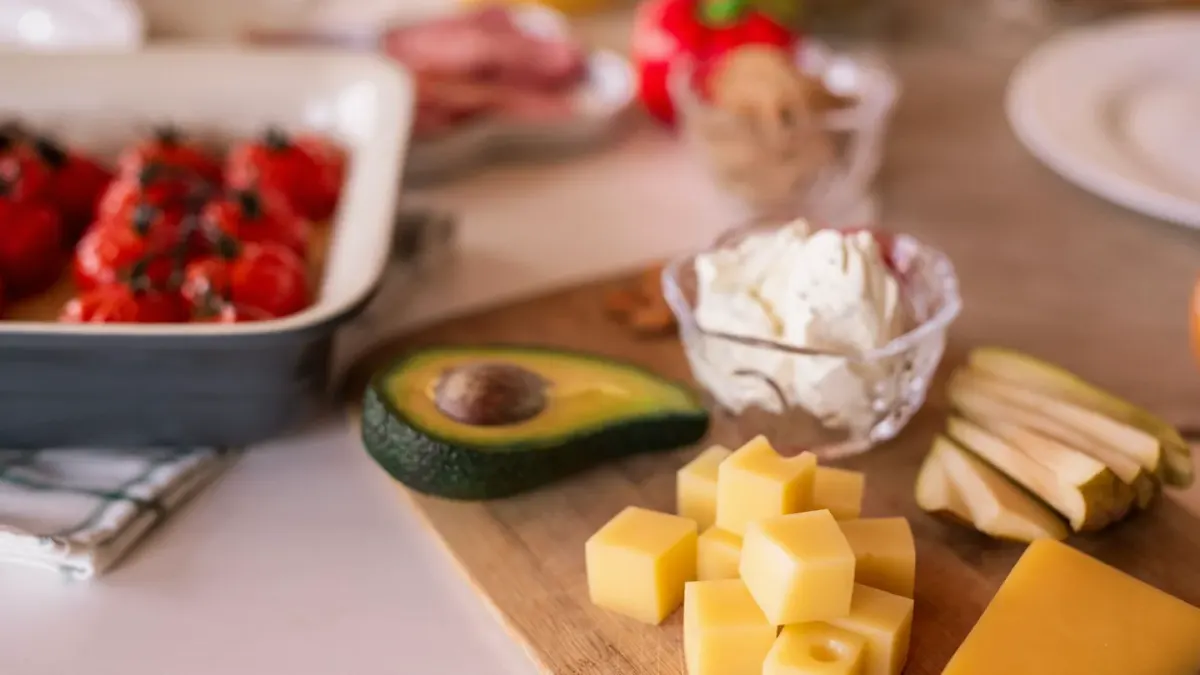 Halved avocado on a wooden cutting board with a dog watching from the edge of the counter