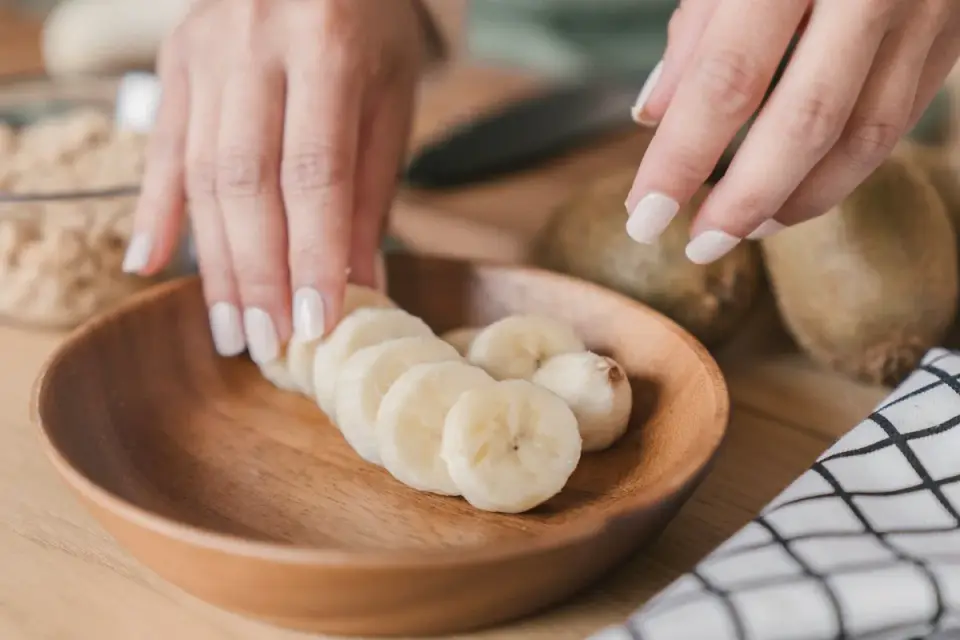 Sliced banana pieces in a small bowl beside a whole banana