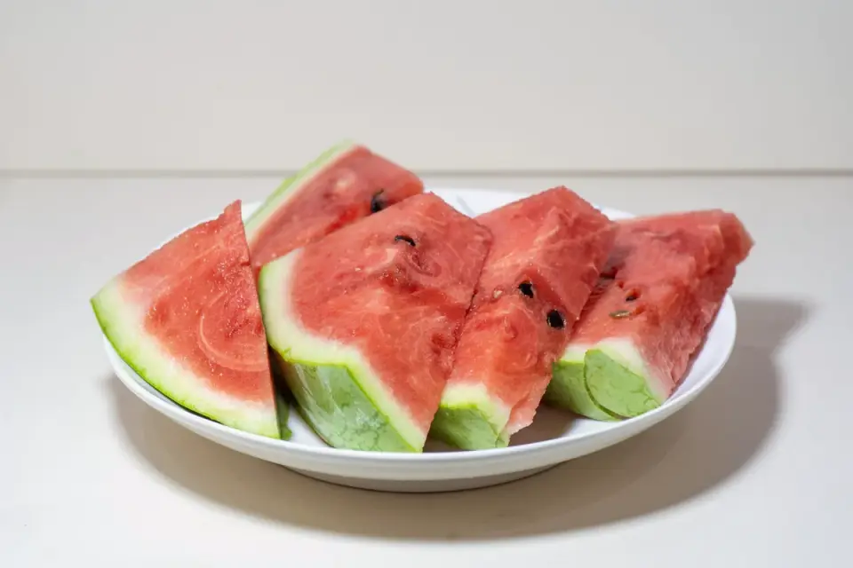 Small seedless watermelon cubes on a cutting board beside a dog bowl
